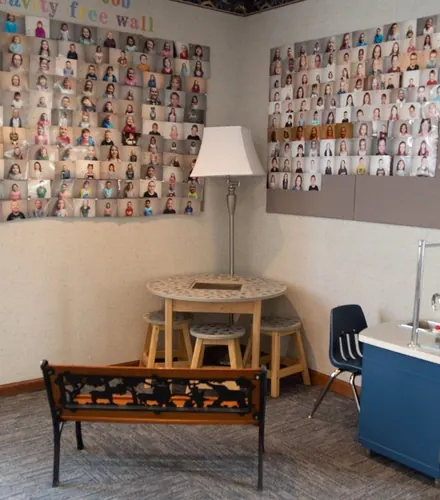 A children's corner with a small table, a bench and walls of patient photographs.